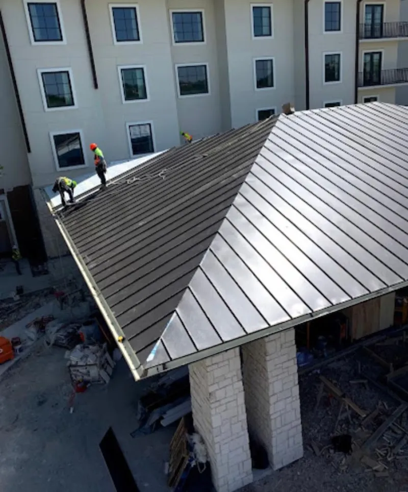 Crew installing standing seam metal roof panels on a commercial project in Worthington